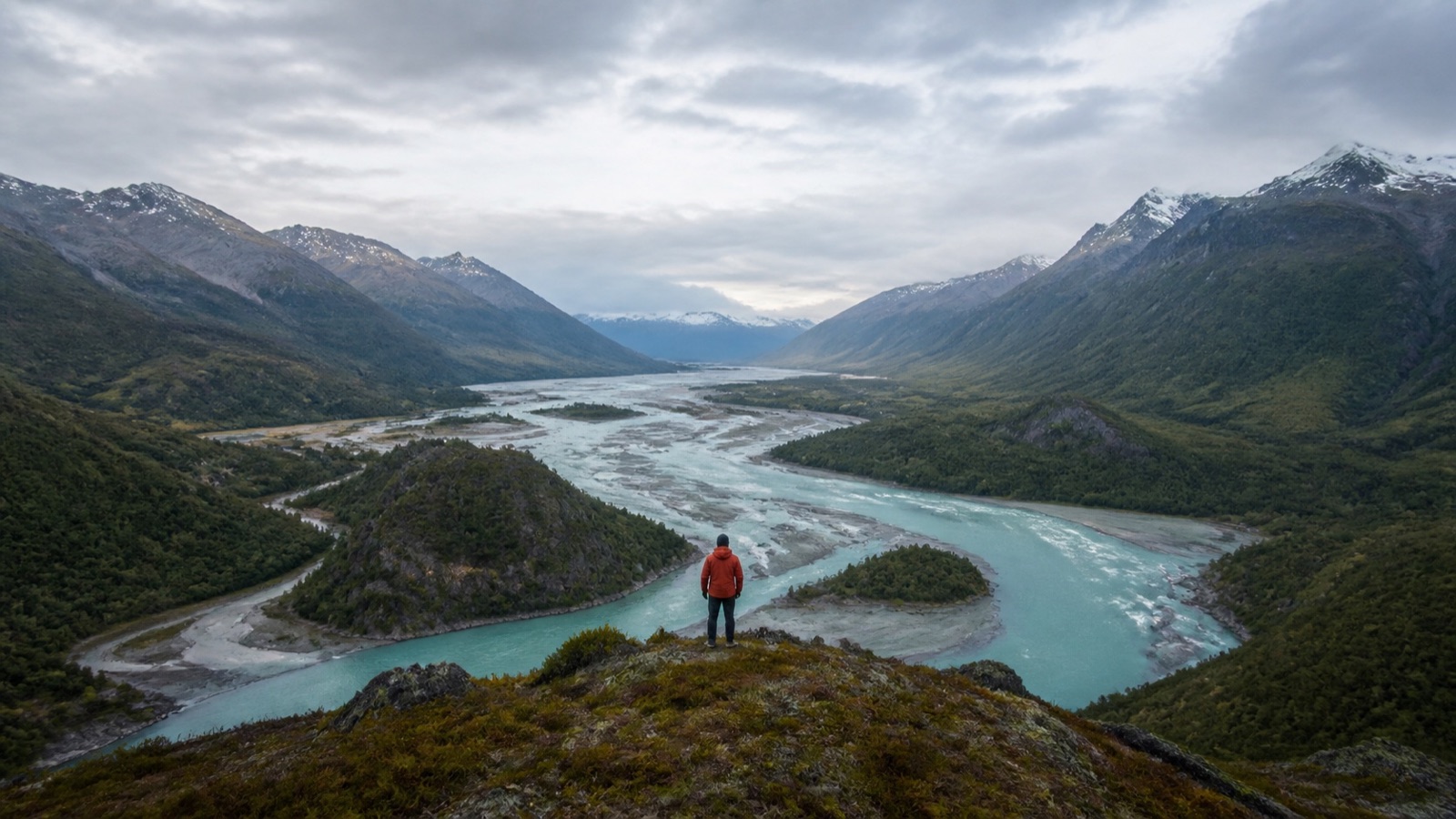 A traveler overlooking a glacial river valley in Patagonia