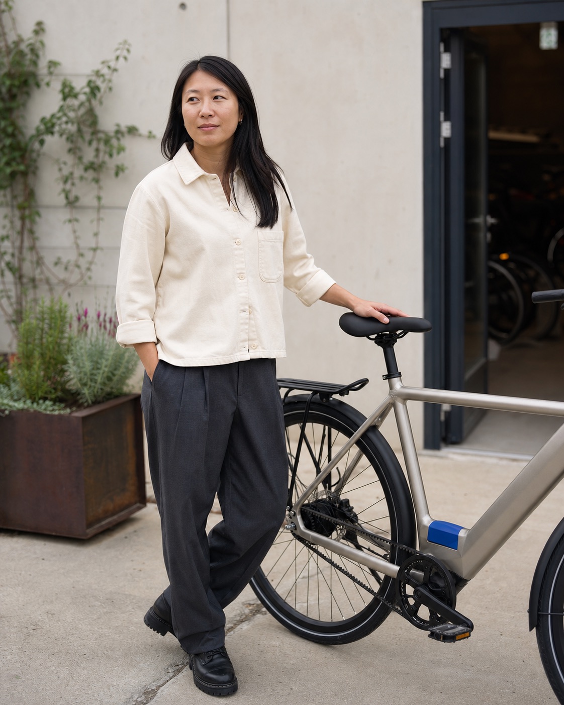 Maya standing beside her silver modular bicycle in a residential courtyard